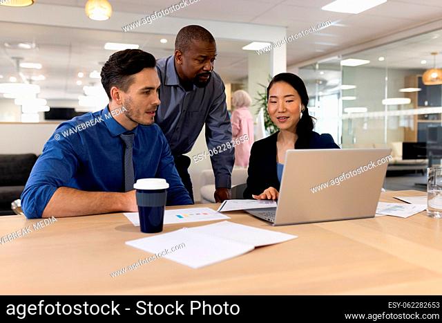 Image of diverse female and male businesspeople working on laptop in office