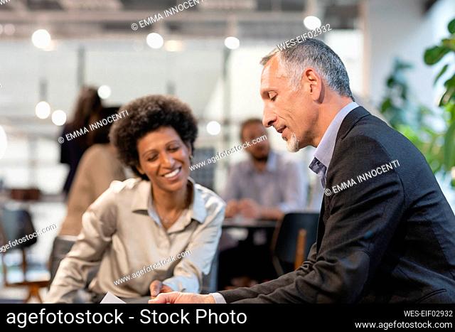 Businessman discussing with smiling colleague in office