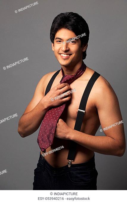 Portrait of shirtless man in suspenders wearing tie