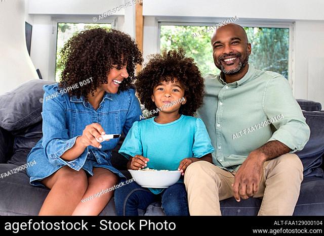 Happy family watching television together while sitting on sofa