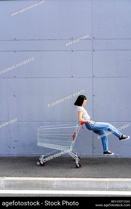 Cheerful woman having fun with shopping cart
