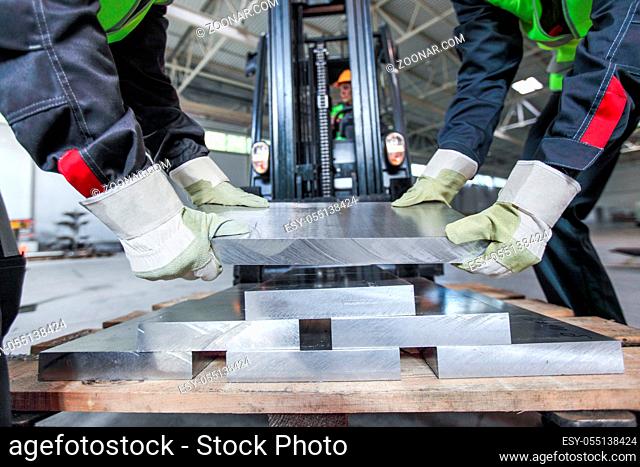 Workers taking aluminium billet at CNC machine shop