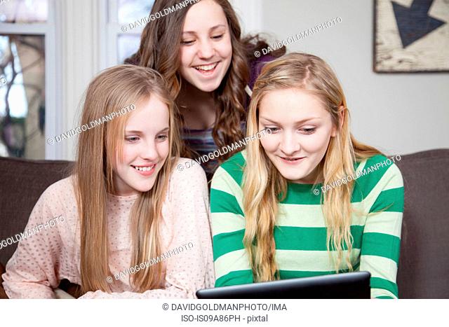 Girls sitting on sofa looking at digital tablet