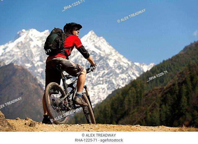 A mountain biker in the Tsum Valley looks at Ganesh Himal mountains, Manaslu region, Himalayas, Nepal, Asia