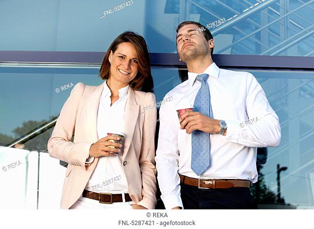 Businessman and businesswoman with coffee to go outdoors