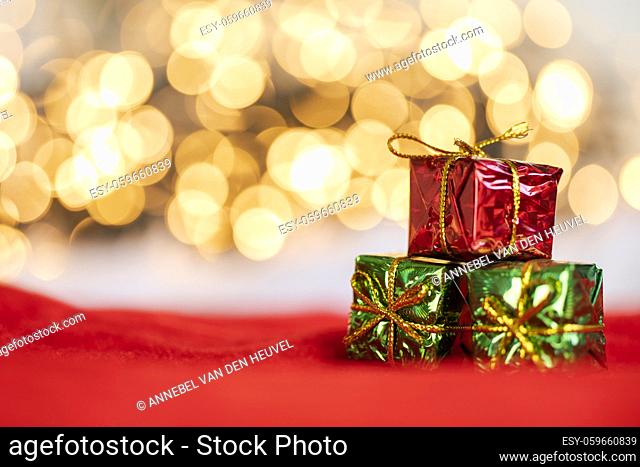 christmas present red and silver baubles against bokeh lights gold shiny glitter background with copy space, space for text