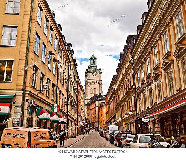 A narrow street in Stockholm with the clock tower of the Church of St. Nicholas (Sankt Nikolai kyrka) also known as Storkyrkan (The Great Church) and Stockholms...