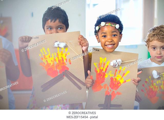 Portrait of smiling children presenting images of fire in kindergarten