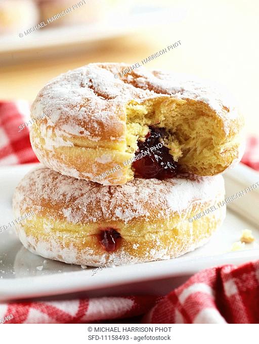 Two Powdered Strawberry Jelly Doughnuts; Stacked; Top Doughnut Bitten