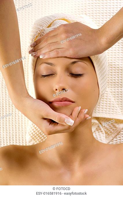 human hands stretching a head of a cute woman in a spa