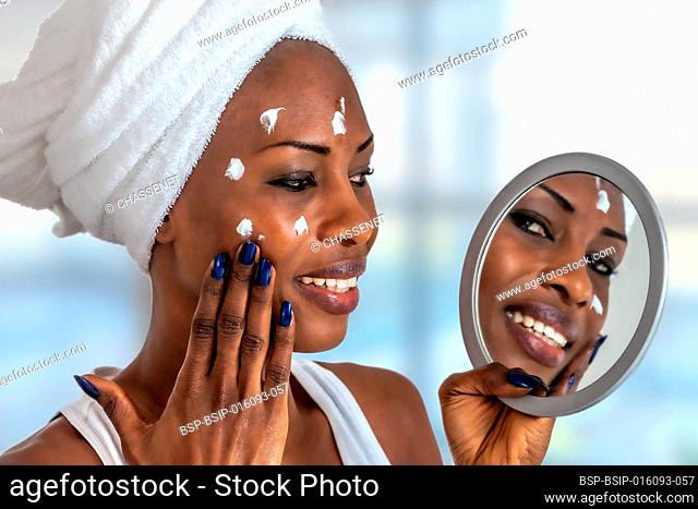 Young girl in front of a bathroom mirror putting cream on a red pimple. Beauty skincare and wellness