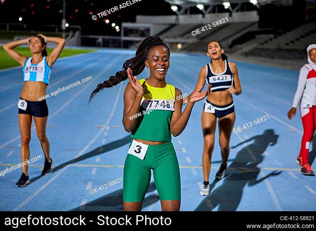 Happy female track and field athlete celebrating after race on track
