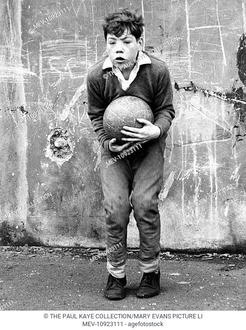 A boy keeping goal in front of a concrete wall in a street in Balham, SW London