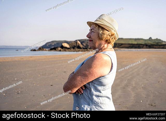 Senior woman with arms crossed standing at beach