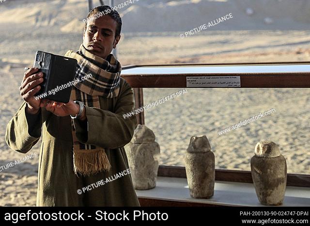 30 January 2020, Egypt, Minya: A man takes a selfie with artifacts found in one of three newly discovered communal tombs of the high priests of ancient Egyptian...