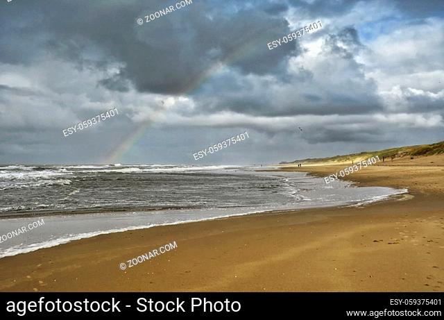 Regenbogen mit Wolken und Sonnenschein am Strand
