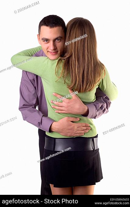 Young man and woman cuddling up to eachother. Man's face to the camera. Isolated on white in studio