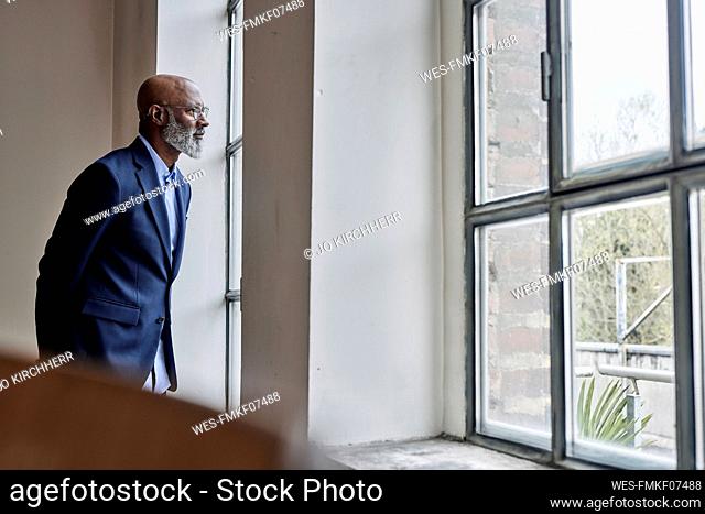 Thoughtful businessman looking through window at home