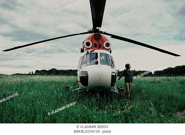 Caucasian woman standing near helicopter in field