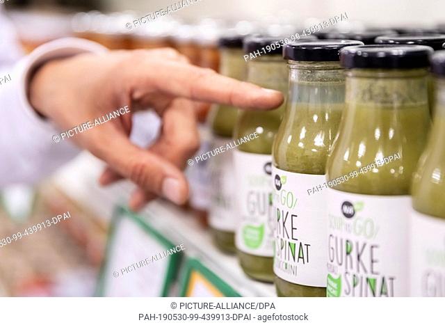 09 May 2019, Berlin: Raphael Fellmer, founder and managing director of ""SirPlus"", points to a bottle of vegetable soup in a supermarket branch in...