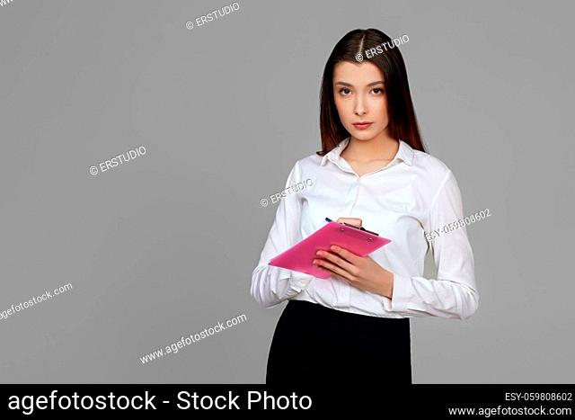 beautiful brunette business woman holding clipboard with papers document on gray background
