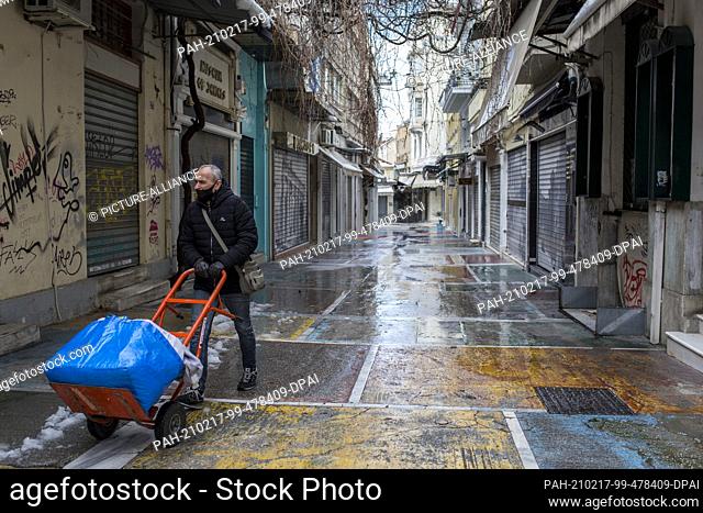 17 February 2021, Greece, Athen: A man pushes a handcart past closed shops in the Monastiraki district of Athens. A strict lockdown has been in effect for the...