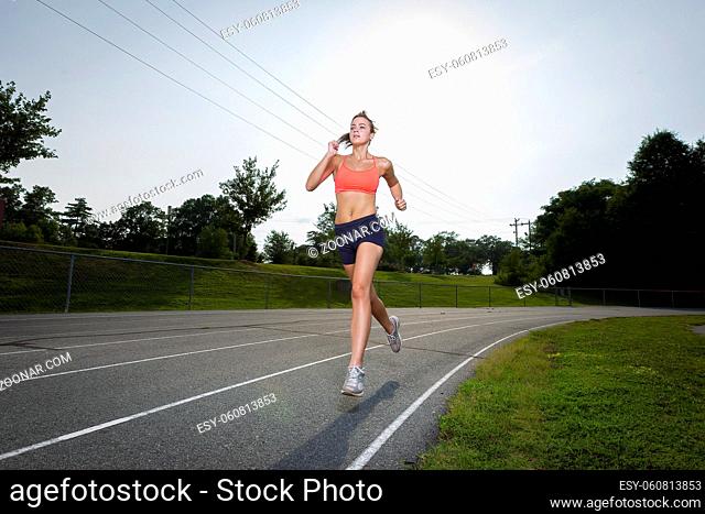 An athletic teenager exercising on a track outdoors