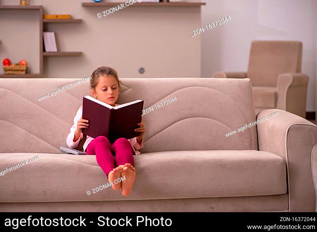 Little girl reading book at home