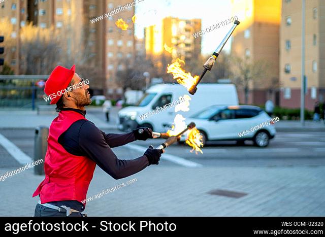 Street performer juggling flaming torches in city