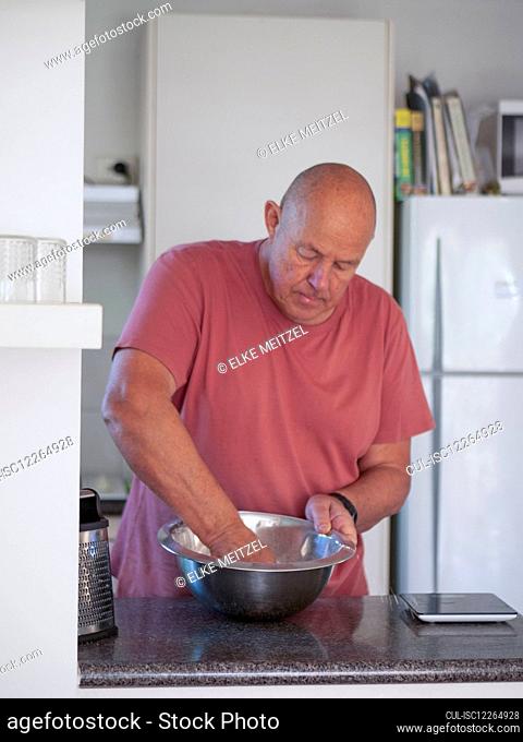 Senior man mixing ingredients for cake