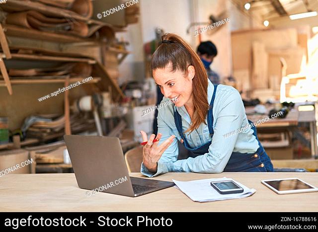 Junge Handwerker Frau beim Videochat mit Kunden am Computer in der Werkstatt