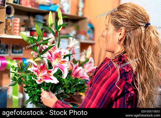 Young female florist with bouquet working in flower shop