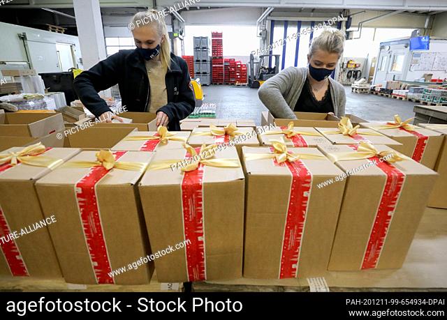 11 December 2020, Mecklenburg-Western Pomerania, Rostock: Sophia Driemel (l) and Dina Gerion are packing Christmas parcels for seafarers at the...
