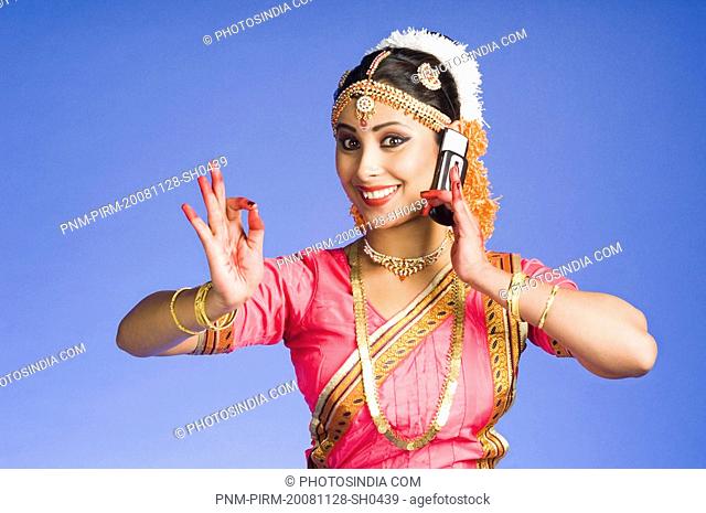 Woman talking on a mobile phone in and performing Bharatnatyam