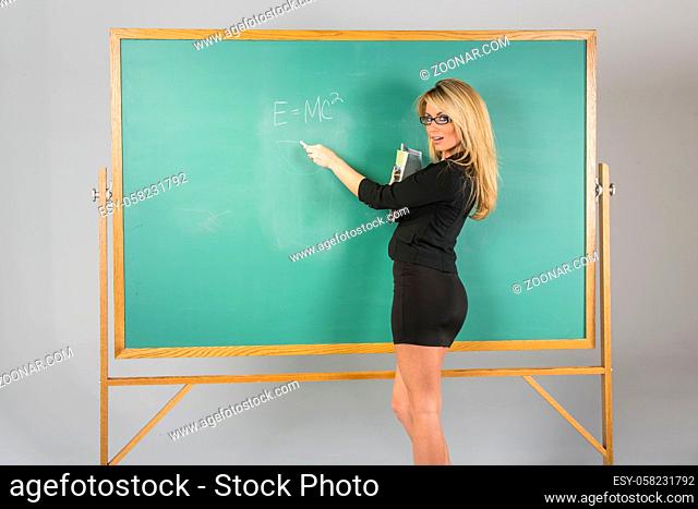 An attractive school teacher in front of a chalkboard. An attractive school teacher in front of a chalkboard