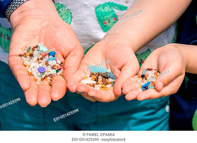 Family of mother and children holding and showing small tiny harmful plastic microbeads collected on the beach in Zante, Zakynthos, Greece