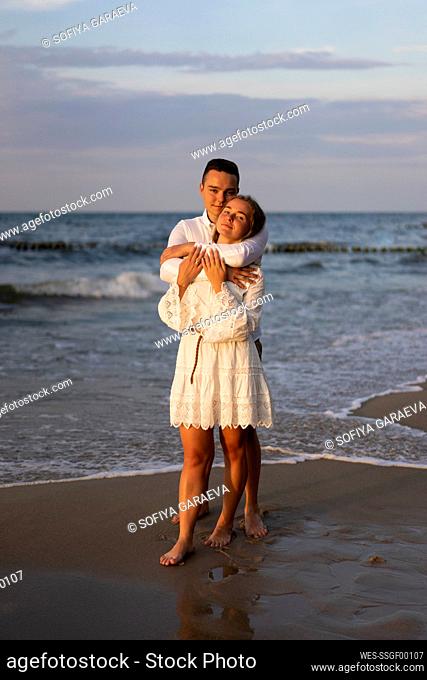Young boyfriend embracing girlfriend in front of sea at beach