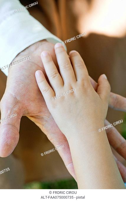 Little girl and grandmother's hands touching