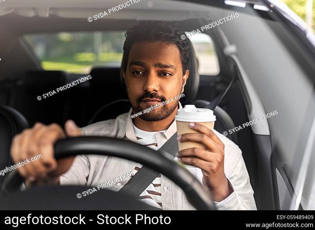 indian man or driver with coffee driving car