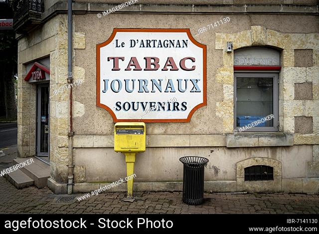 Billboard on the wall of the shop Le D'Artagnan with letterbox and wastepaper basket in front of it, historic old town of Auch, Département Gers, Occitanie