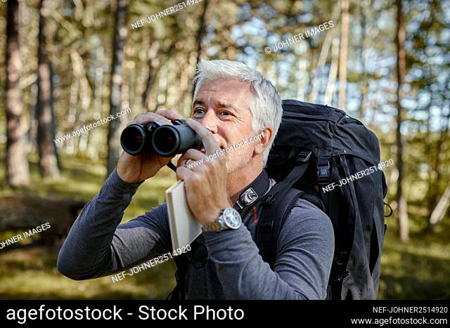 Man in forest holding binoculars