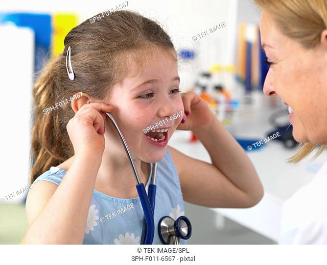Doctor comforting a 5 year old Girl by playing with her stethoscope in a clinic