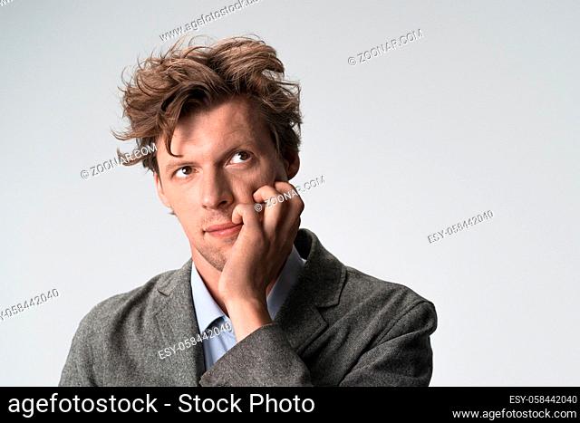 Thoughtful man looking up to side grabbing his face with his hand. Copy space