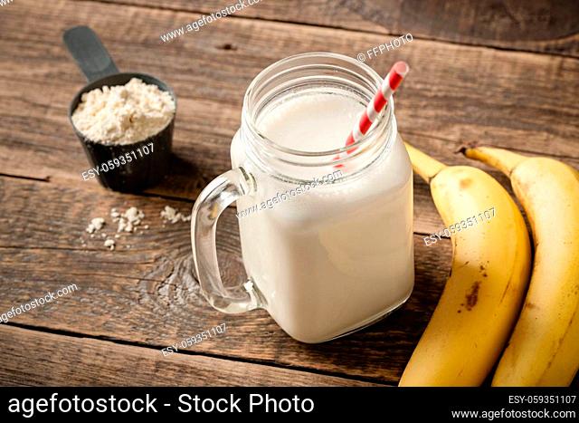 Whey protein cocktail and banana fruit on wooden table