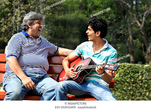 Father listening to his son play the guitar