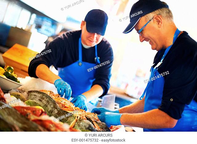 Closeup of smiling fishmongers unpacking fresh fish and seafood