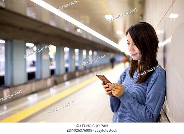 Woman use of mobile phone in train station