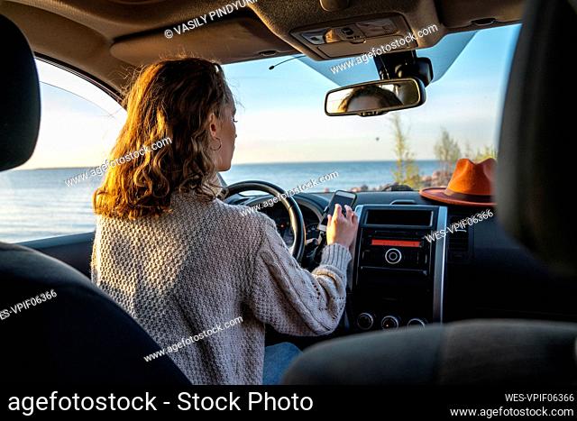 Young woman using smart phone sitting in car