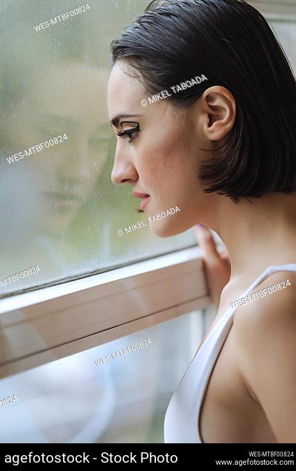 Close-up of thoughtful young woman looking through window in ballet studio