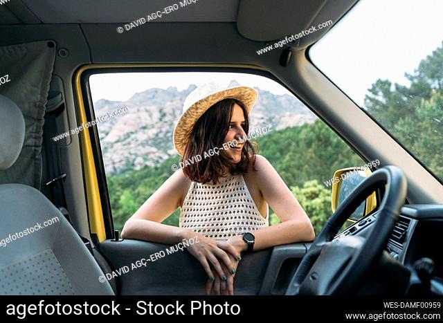 Smiling young woman wearing hat seen through van window